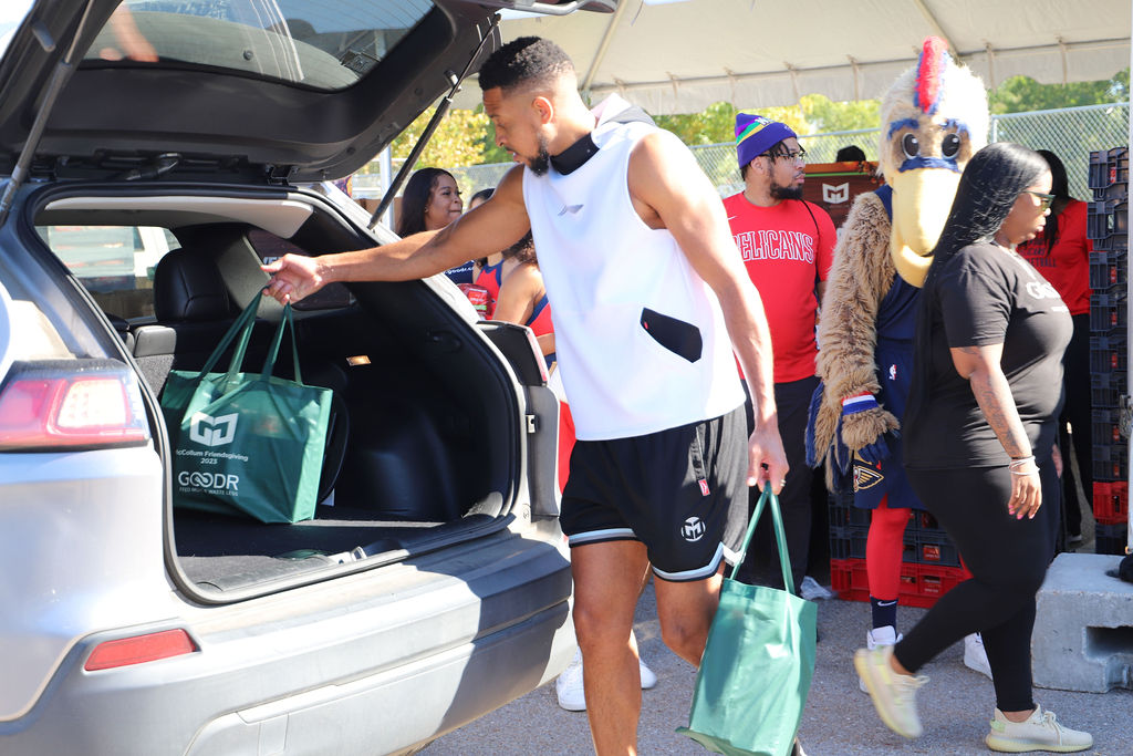 Goodr partner, CJ McCollum, loads green bags filled with shelf-stable Thanksgiving groceries